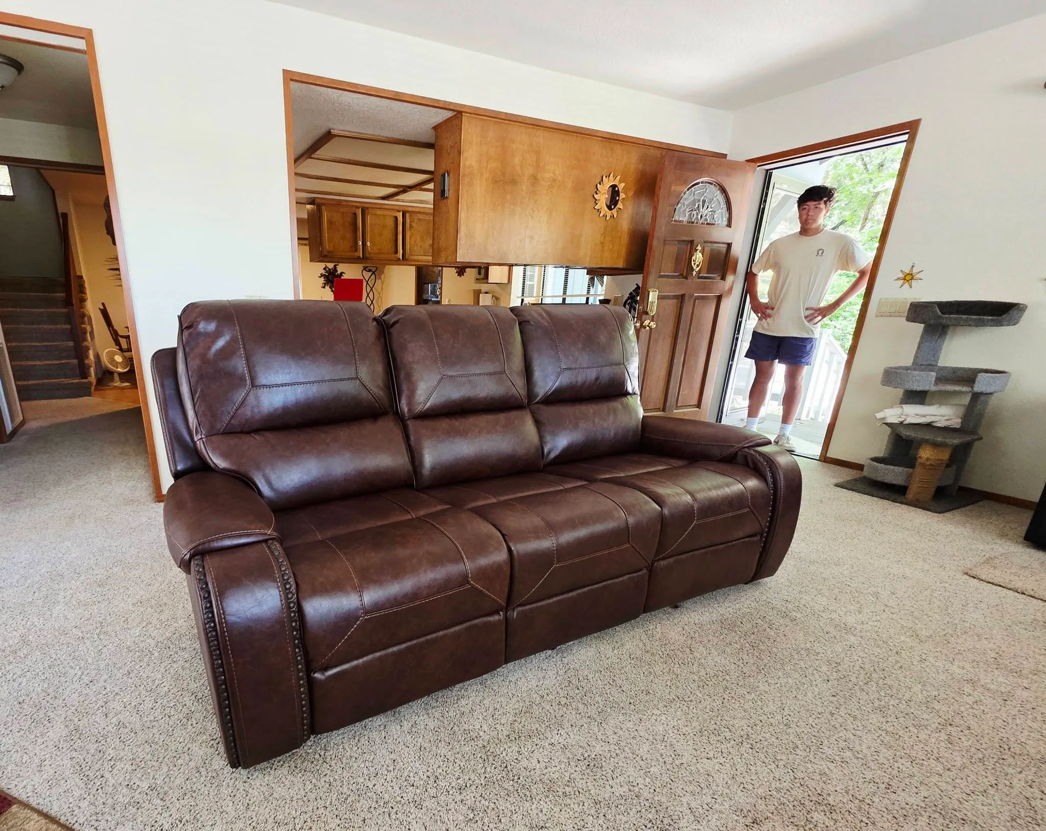 A large leather reclining sofa just delivered into a local family's living room, BoxDrop team member at the door