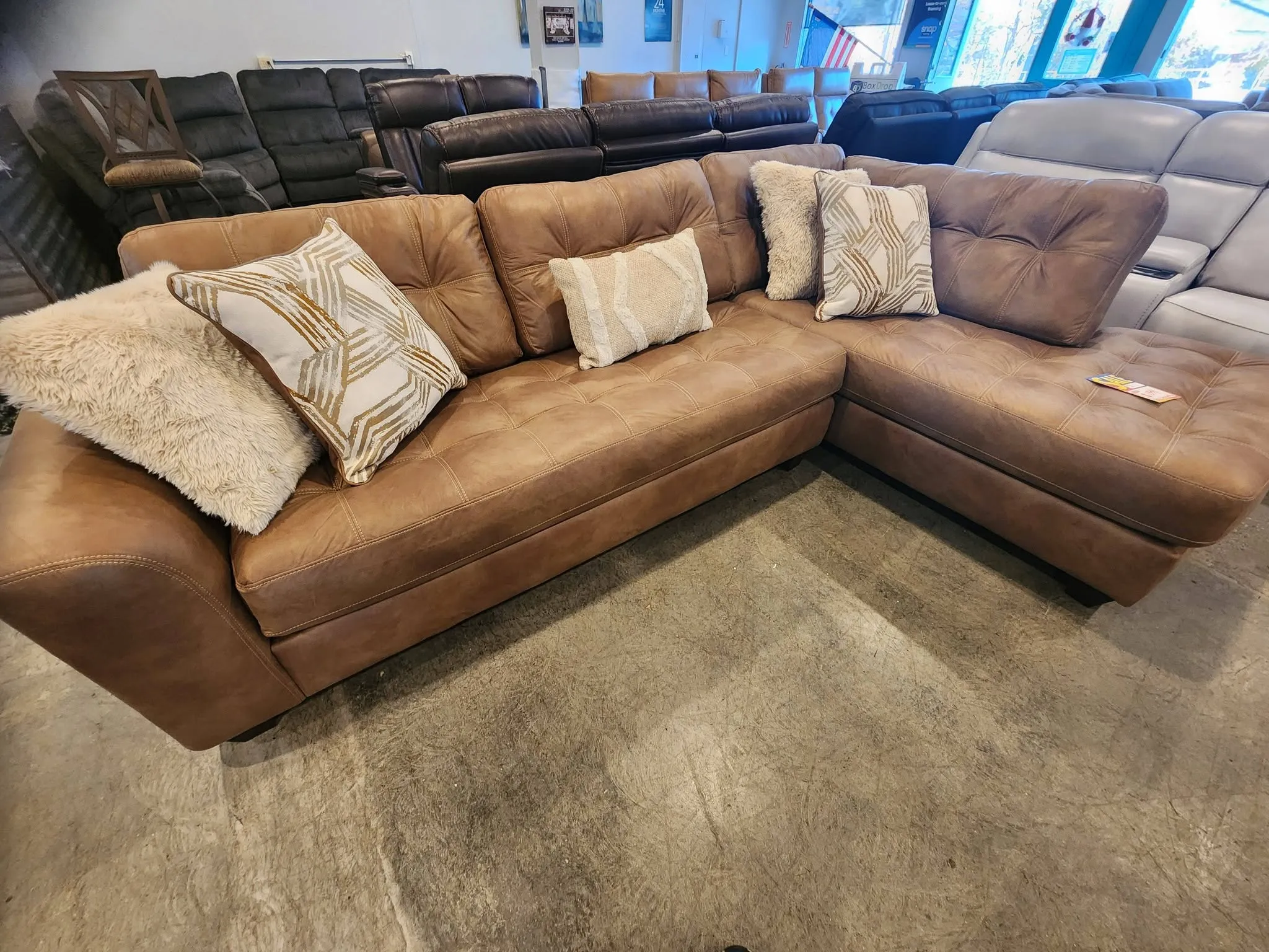 A large camel-toned leather sectional with accent pillows at BoxDrop Grass Valley